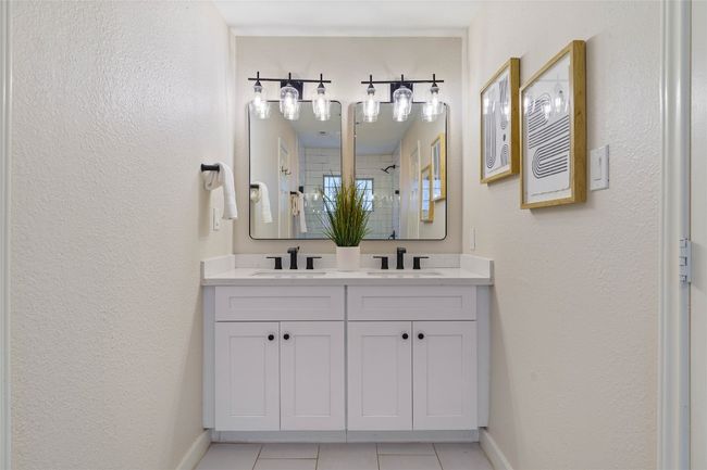 Bathroom featuring walk in shower, tile patterned flooring, a sink, and double vanity | Image 23