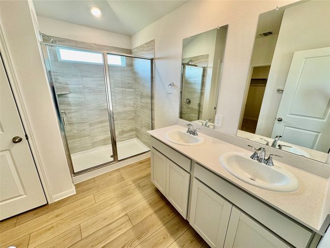 Full bathroom featuring wood finished floors, a stall shower, and double vanity | Image 4