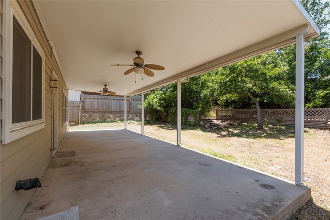 Fenced backyard with a ceiling fan and a patio area | Image 24