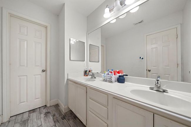 The upstairs full bathroom offers functionality for busy mornings, featuring a dual-sink vanity with expansive counter space and a large mirror. Durable wood-look tile flooring ties into the home’s cohesive finishes, while the layout provides excellent flow for shared use. | Image 27
