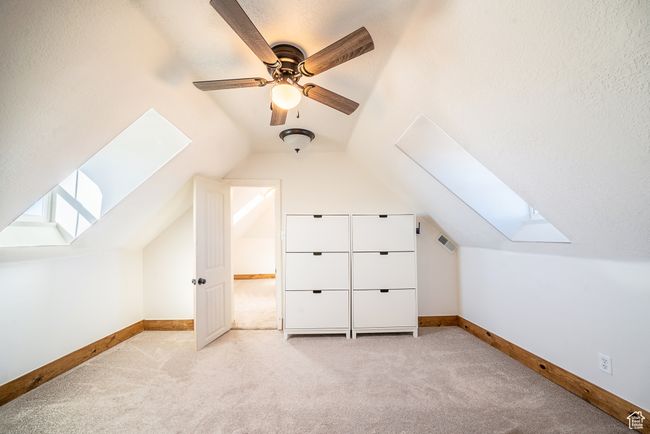 Bonus room with lofted ceiling with skylight, carpet flooring, ceiling fan, and baseboards | Image 16