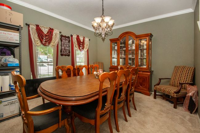 Dining room featuring a chandelier, ornamental molding, and light carpet | Image 4