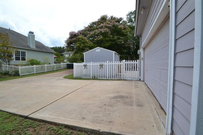 View of patio / terrace featuring a storage shed, a garage, and concrete driveway | Image 23