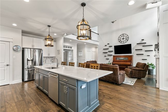 Kitchen with appliances with stainless steel finishes, decorative light fixtures, dark hardwood / wood-style flooring, sink, and white cabinets | Image 14