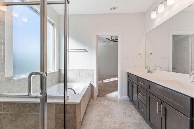 Full bath featuring visible vents, a sink, tile patterned flooring, double vanity, and a bath | Image 11