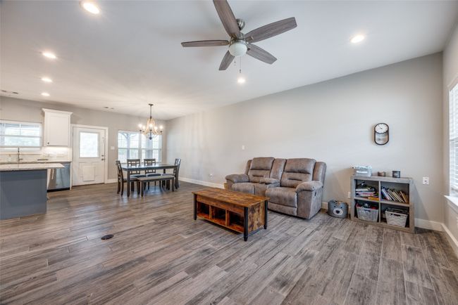 Living area featuring dark wood-type flooring, a chandelier, a ceiling fan, recessed lighting, and baseboards | Image 4