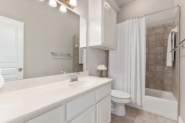 Hall bath with tiled tub surround and extended vanity. | Image 26