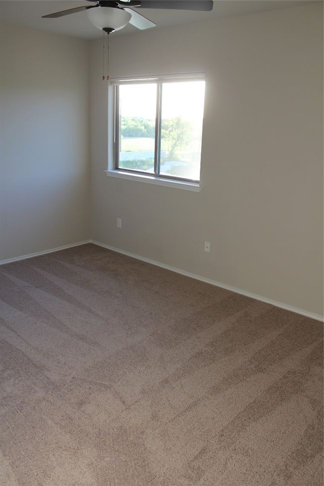 Carpeted empty room with ceiling fan and baseboards | Image 13