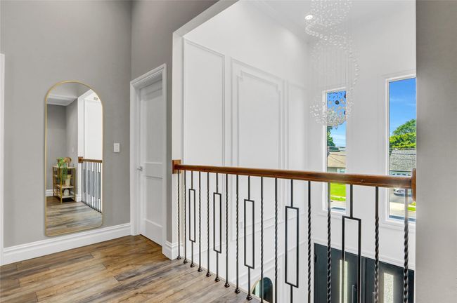 Corridor featuring wood finished floors, arched walkways, a chandelier, a towering ceiling, and baseboards | Image 25