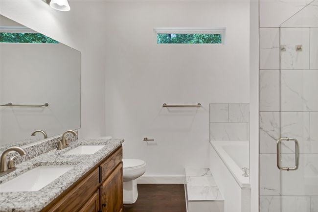 Full bathroom featuring a bath, double vanity, a stall shower, and wood finished floors | Image 17