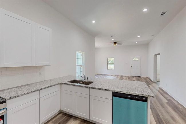 Kitchen with ceiling fan, light hardwood / wood-style flooring, stainless steel dishwasher, backsplash, and sink | Image 11