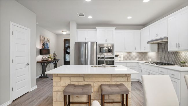 Kitchen featuring visible vents, under cabinet range hood, tasteful backsplash, light wood finished floors, and stainless steel appliances | Image 7