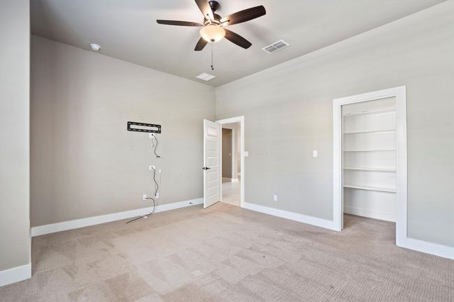 Unfurnished bedroom featuring light colored carpet, a spacious closet, and ceiling fan | Image 26