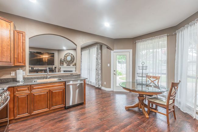 Kitchen featuring appliances with stainless steel finishes, arched walkways, brown cabinetry, dark wood finished floors, and recessed lighting | Image 13