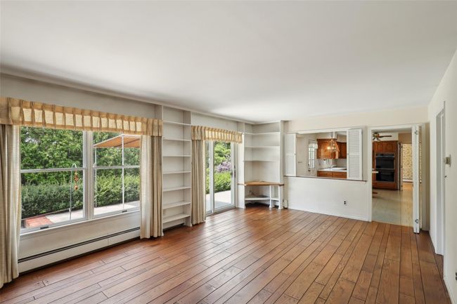 Unfurnished living room with baseboard heating, wood-type flooring, and ceiling fan | Image 15