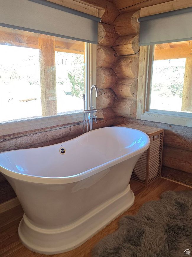 Full bath featuring rustic walls, a soaking tub, and wood finished floors | Image 76