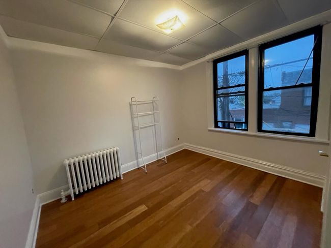 Unfurnished room featuring radiator, dark wood finished floors, and baseboards | Image 8