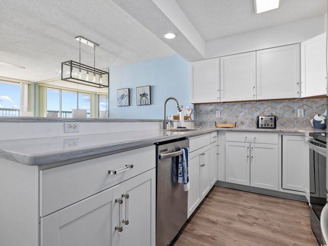 Kitchen featuring a sink, backsplash, dishwasher, and light countertops | Image 11