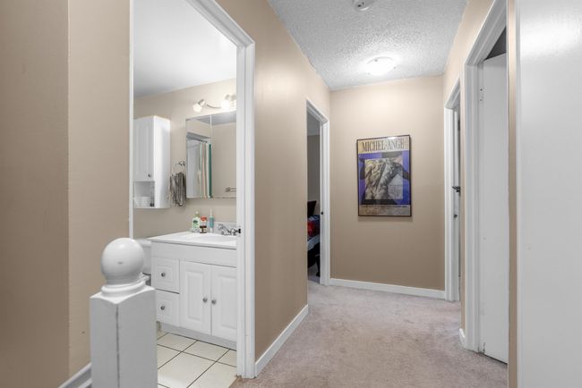 Hallway featuring baseboards, light colored carpet, a sink, and a textured ceiling | Image 17