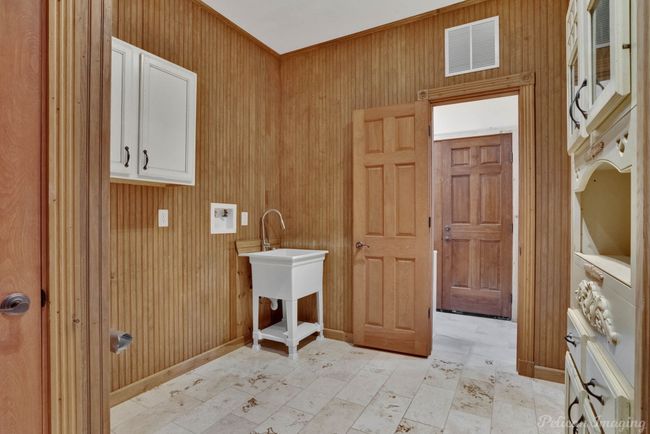 Laundry room featuring cabinet space, wooden walls, and stacked washer / drying machine | Image 27