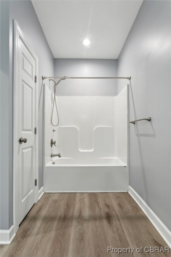 Bathroom with washtub / shower combination, wood finished floors, and baseboards | Image 26