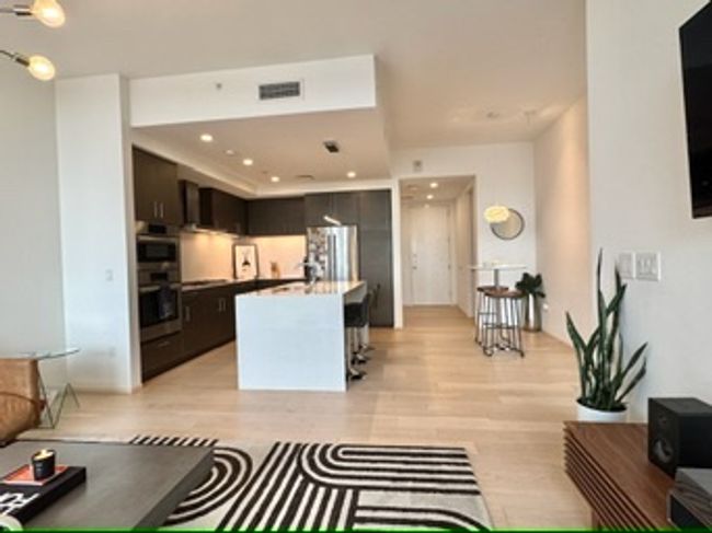 Kitchen with double oven, light wood-style floors, dark brown cabinetry, recessed lighting, and a center island | Image 20