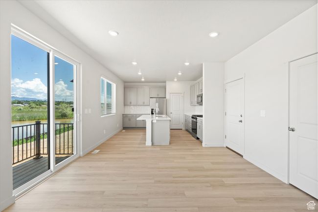 Kitchen with appliances with stainless steel finishes, light wood-style flooring, recessed lighting, a center island with sink, and light countertops | Image 16