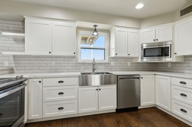 Kitchen featuring visible vents, dark wood-style flooring, a sink, light countertops, and appliances with stainless steel finishes | Image 13