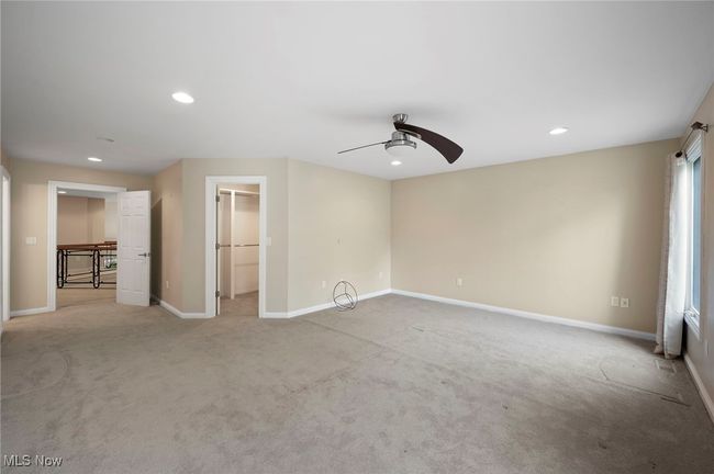 Unfurnished bedroom featuring light carpet, recessed lighting, a walk in closet, a ceiling fan, and a closet | Image 28