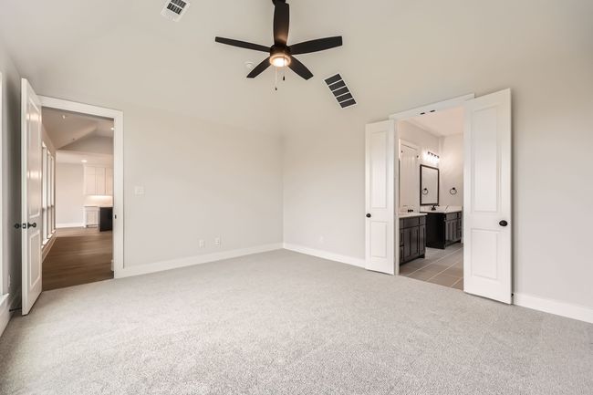 Unfurnished bedroom with connected bathroom, baseboards, light colored carpet, and visible vents | Image 15