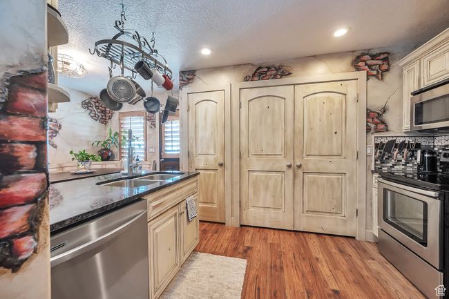 Kitchen with recessed lighting, light wood-style floors, cream cabinets, a textured ceiling, and appliances with stainless steel finishes | Image 13