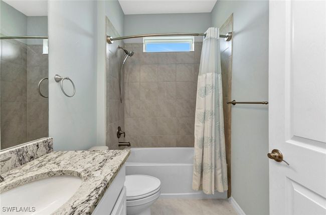 Bathroom with toilet, shower / tub combo, vanity, and tile patterned flooring | Image 14