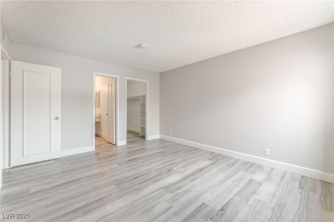 Unfurnished bedroom featuring light wood-style flooring, a textured ceiling, a spacious closet, and a closet | Image 14