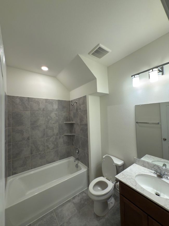 Full bath featuring toilet, vanity, shower / tub combination, and tile patterned flooring | Image 6