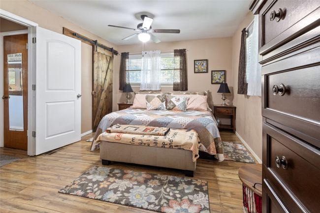 Bedroom with a barn door, light wood-type flooring, and a ceiling fan | Image 10