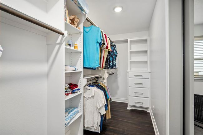 Primary Walk-in Closet features wardrobe built-ins and adjustable shelving. | Image 21