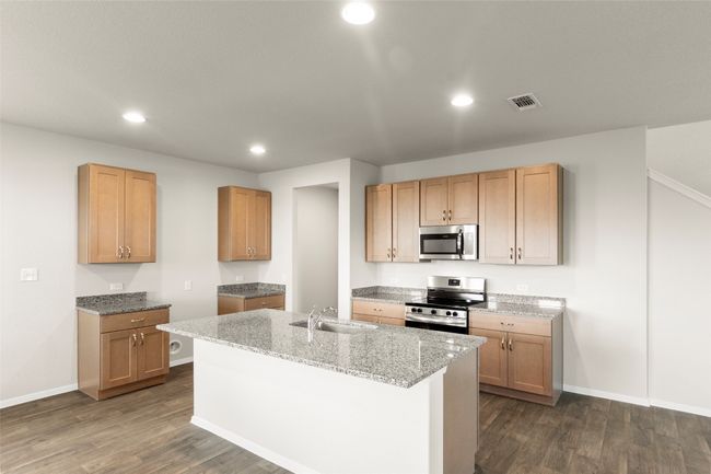 Kitchen featuring appliances with stainless steel finishes, dark wood finished floors, recessed lighting, a kitchen island with sink, and light stone countertops | Image 19