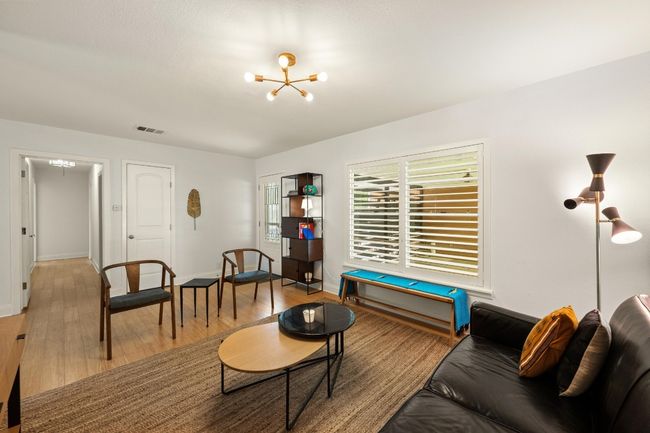 The living room is spacious and features a stylish light fixture. | Image 5