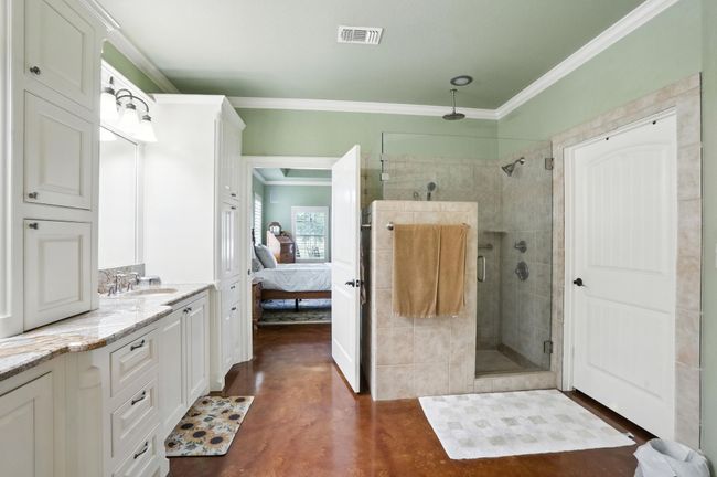 Full bathroom featuring finished concrete flooring, a stall shower, crown molding, vanity, and ensuite bath | Image 16