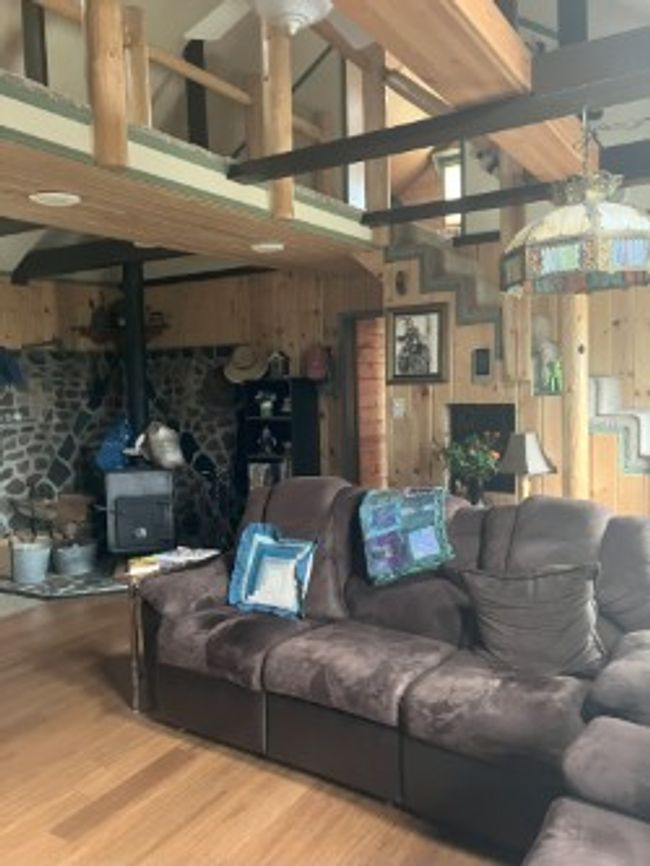 Living room with wood finished floors, a wood stove, a towering ceiling, and wooden walls | Image 26