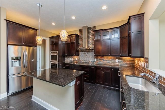 Kitchen featuring a sink, stainless steel appliances, dark wood finished floors, and wall chimney exhaust hood | Image 11