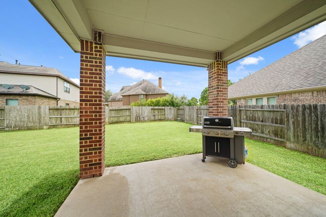 This backyard features a covered patio with brick columns, a well-maintained lawn, perfect for outdoor entertaining. The area is fenced for privacy, offering a cozy and secure space. | Image 33