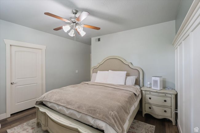 Primary Bedroom with dark wood-type flooring, visible vents, and a ceiling fan | Image 13