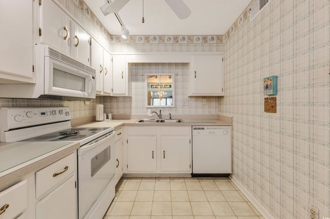 Kitchen featuring white appliances, light countertops, a sink, and a ceiling fan | Image 6