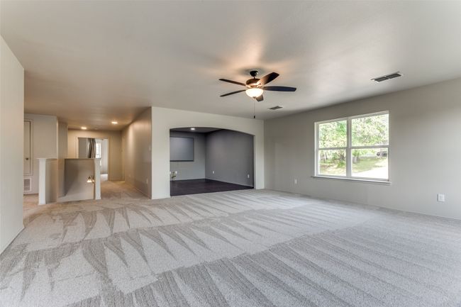 Unfurnished living room featuring carpet flooring, a ceiling fan, and arched walkways | Image 30