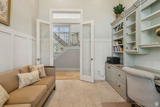 Office area with a decorative wall, french doors, wainscoting, built in study area, and light carpet | Image 26
