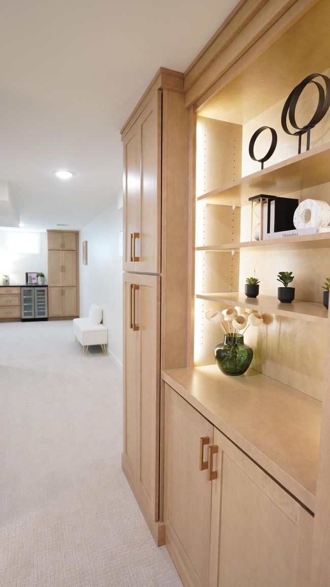 Custom cabinetry abounds in this home, including in the cohesively stained birch cabinets of both the large storage cabinet and the dry bar down the hall. The light gold hardware adds a touch of elegance in this warm and inviting space. | Image 35