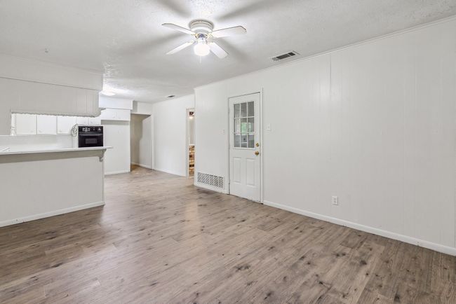 Unfurnished living room with a ceiling fan, light wood-type flooring, a textured ceiling, and ornamental molding | Image 20