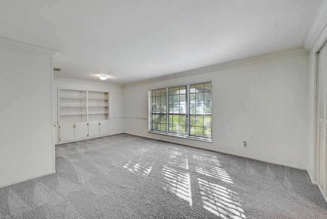 Carpeted spare room with built in features, baseboards, and crown molding | Image 7