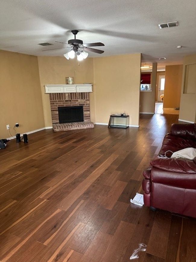 Living room featuring a ceiling fan, wood finished floors, and a fireplace | Image 22